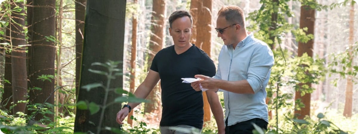 header twee mannen in het bos kijkend op een papiertje
